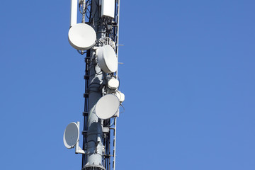 Close up white color antenna repeater tower on blue sky