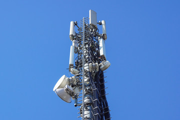 Close up white color antenna repeater tower on blue sky