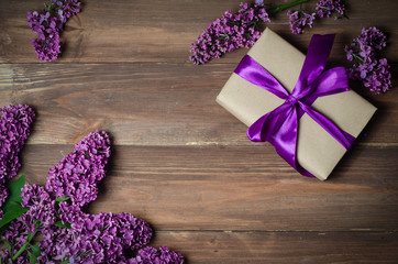 Obraz na płótnie Canvas Gift box with purple bow and lilac on wood