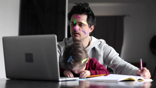 young father works at a computer at home with a child