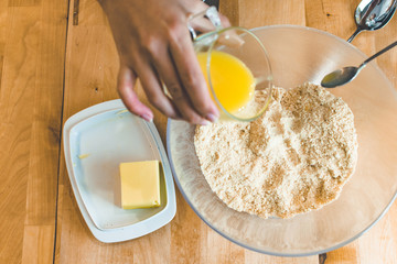 .Adding melted butter to csmashed cookies for preparing cheesecak