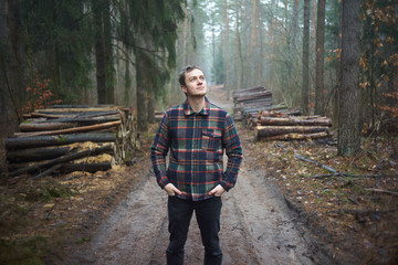 Caucasian man has a walk in foggy forest and enjoys environment