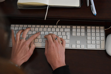 Remote working concept. A close up of a young woman typing on a keyboard at a desk in a home