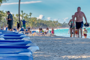 Blue chairs lined up on a beach, blurred people, Dominican republic
