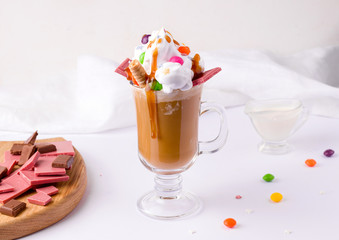coffee with cream and caramel decorated with sweets and chocolate on a white background