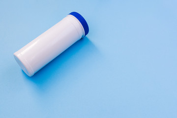 White plastic bottle with a blue cap without a label with copy space. Bank for storage of hygiene products, wet wipes, cotton pads. Cosmetic products on a blue background.