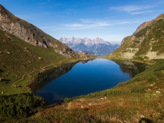 Fototapeta na wymiar flowing of the wild lake in Austrian Alps, epic landscape scenery, snowy mountains in back
