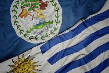 waving colorful flag of uruguay and national flag of belize.