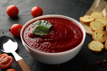 Tomato cream soup on black background, close up