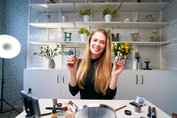 Beauty blogger woman filming daily make-up routine tutorial near camera on tripod. Influencer...