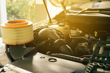 Cropped image of handsome young auto mechanic in uniform repairing car Change car air filter in...