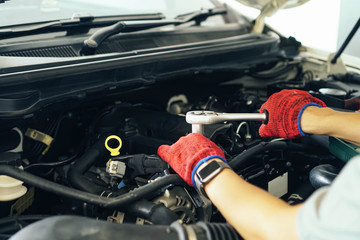 Cropped image of handsome young auto mechanic in uniform repairing car in auto service.selective focus.