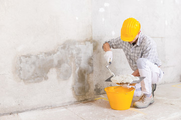 Plasterer loading new plaster from a bucket