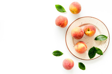 Summer fruits. Ripe red peaches on plate on white table top-down copy space