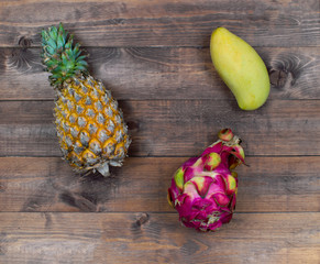 Exotic asia fruits on brown wood background. Assorted tropical summer fruits. Mango, dragon fruit,...