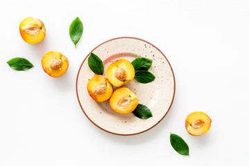 Healthy food. Ripe sliced peaches on plate on white table top-down