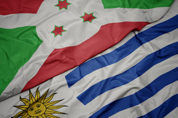 waving colorful flag of uruguay and national flag of burundi .