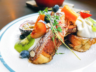 Delicious sweets French toasts with vanilla yogurt, blueberries jam and fresh fruits for a vitamin breakfast.