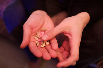A man holds pills in his hands. Male hands hold many pills. Hands hold pink, white pills, medicine. Coronavirus tablets.