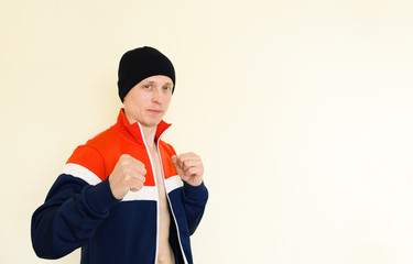 Young man in a sports jacket on a white background shows fists