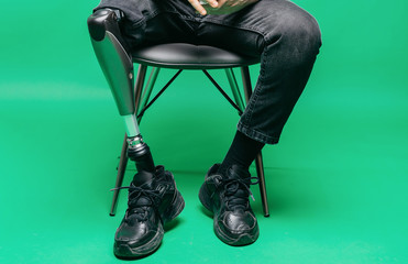 Cropped view of disabled young man with prosthetic leg, artificial limb concept. Studio shooting on...