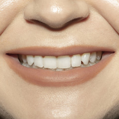 Smiling. Close-up shoot of female mouth with natural nude gloss lips make-up and well kept cheeks skin. Cosmetology, medicine, dentistry and beauty care, emotions and facial expression concept.