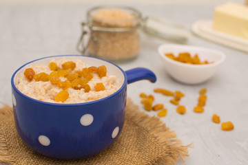 Wheat porridge with raisins in a blue ceramic cup on a napkin. Wheat porridge for breakfast. Vegetarian breakfast.