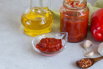 Aivar in a bowl and in a glass jar, as well as inradients for its preparation - pepper, garlic, vegetable oil
