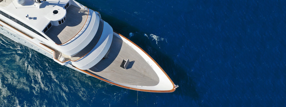 Aerial drone ultra wide photo of luxury mega yacht with wooden deck anchored in deep blue sea of Mykonos island, Cyclades, Greece