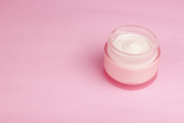 Cosmetic face or body cream container with water drops on pink background. Moisturizing skin Cream concept