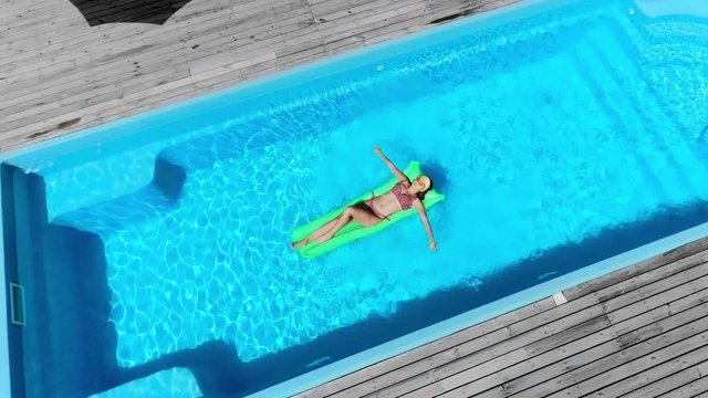 sexy girl relaxing on pool float in swimming pool in summer