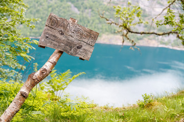 GEIRANGER, NORWAY - 2016 JUNE 12.  Danger sign above Geiranger fjord on the hiking track.