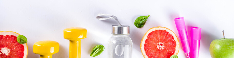 Fitness and healthy food lifestyle concept. Dumbbells, diet fruit and vegetable lunch box, water and jump rope on white background. Flatlay image, top view copy space