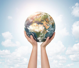 Child hands holding planet earth over blue sky background with copy space © rangizzz