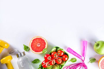 Fitness and healthy food lifestyle concept. Dumbbells, diet fruit and vegetable lunch box, water and jump rope on white background. Flatlay image, top view copy space