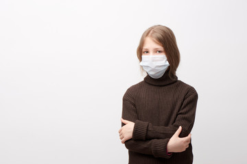 Unhappy young girl wearing face mask and brown neck sweater hugging herself