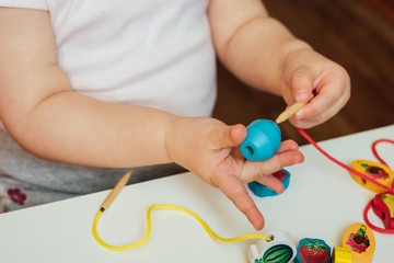 Child putting beads on a string. Bead stringing activity. Fine motor skills development. Lacing,...