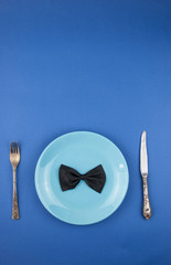 ceramic plate with a cutlery and gift box on the blue paper background