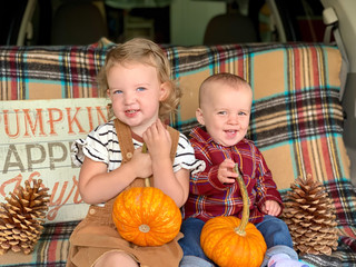 Fototapeta premium Cute little kids with their pumpkins in tailgate of family car