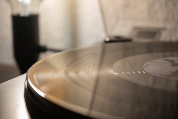 Vintage record player with vinyl disc, close to light.