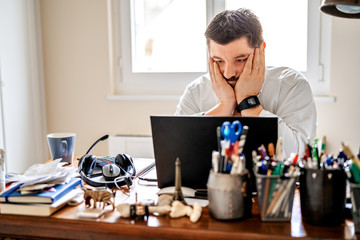 Tired frustrated businessman working from home online sitting at home office with laptop during...