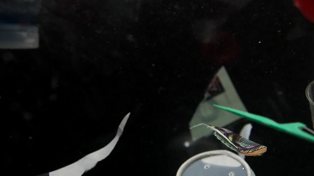 variety of plastic and food trash garbage floats in water on a black background slow motion video in high quality, environmental problems, ocean pollution. High quality video in 4K. Video is Loopable