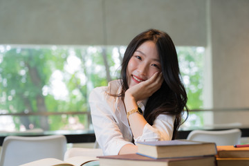 Obraz premium Beautiful student wearing white shirt resting while reading books on the table in library