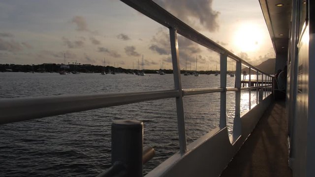 Shot of the rising sun above a lake trough the fence of a ferry boat in slow motion