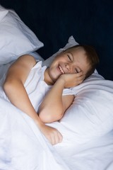 Fototapeta na wymiar Young boy lies in bedroom and smiles