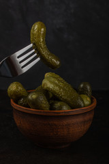 Gherkins and sauerkraut in a clay bowl on a dark concrete background