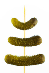 Three gherkins on a skewer, on a white background