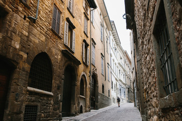 Quarantine in Italy, a lonely man walks along the deserted streets of the old city of Bergamo