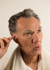 Obraz premium Man Cleaning his Ear with a Cotton Tip Swab 