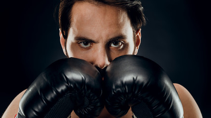 A man in Boxing gloves. A man Boxing on a black background. The concept of a healthy lifestyle